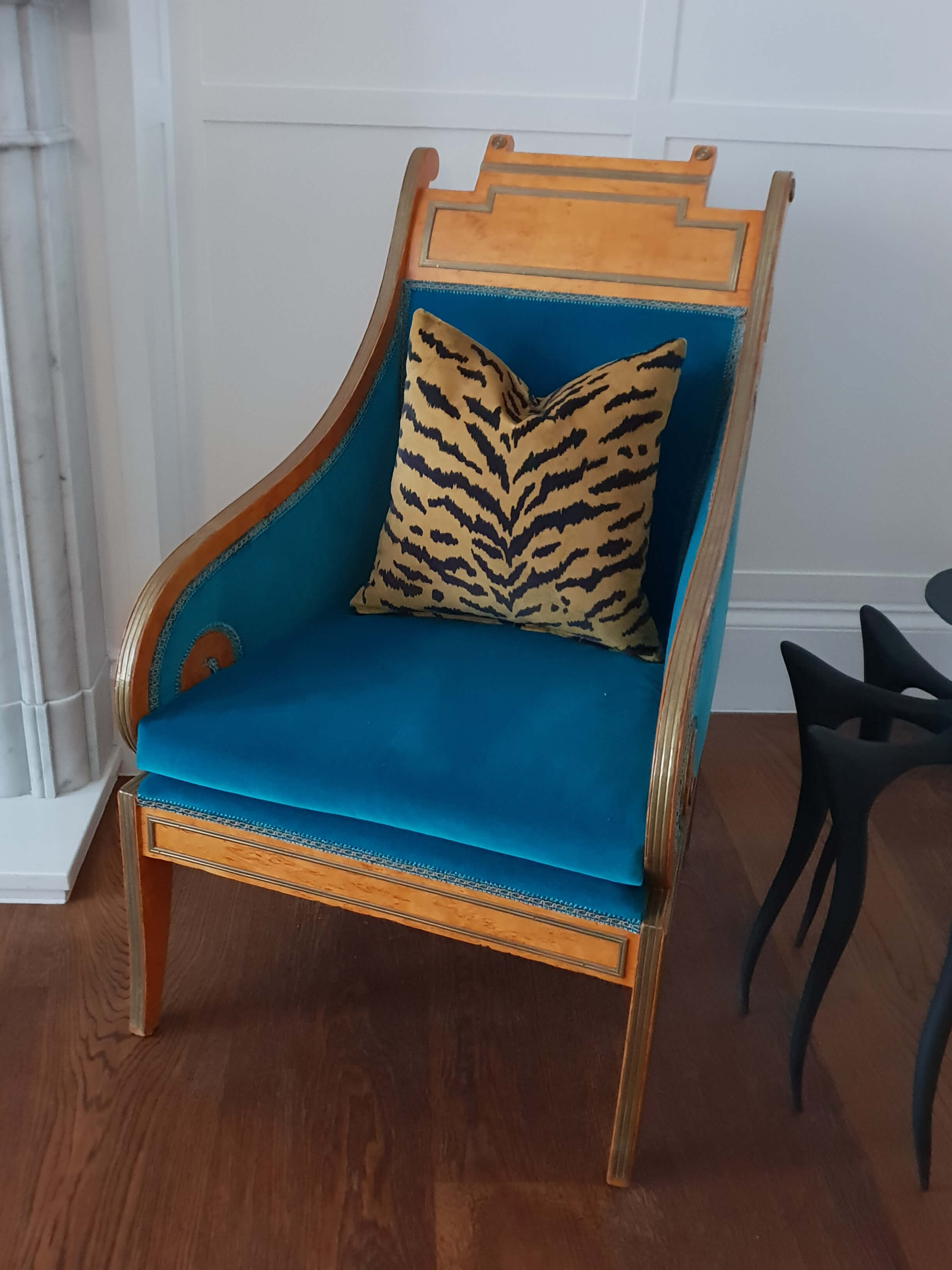 Upholstered chair in blue fabric with tiger pattern cushion