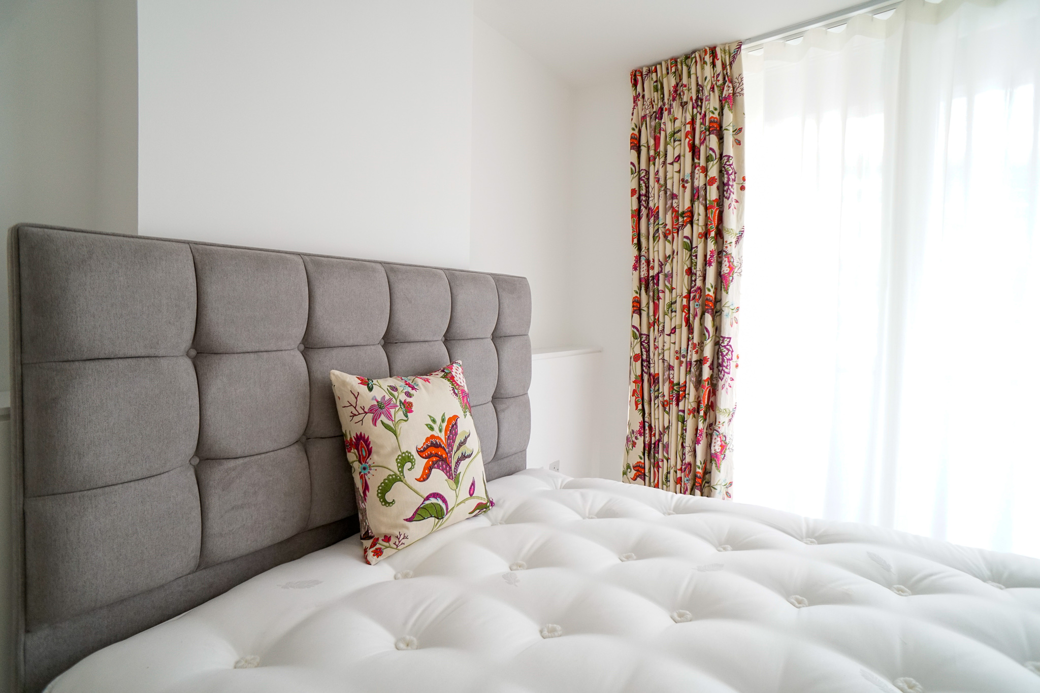 Headboard with upholstered cushion and bespoke curtains